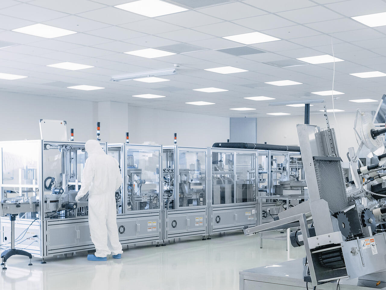Produktionshalle Halbleiterforschung mit Wissenschaftlern in Schutzausrüstung an Maschinen