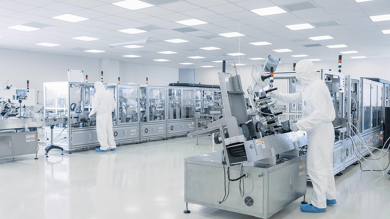 Produktionshalle Halbleiterforschung mit Wissenschaftlern in Schutzausrüstung an Maschinen