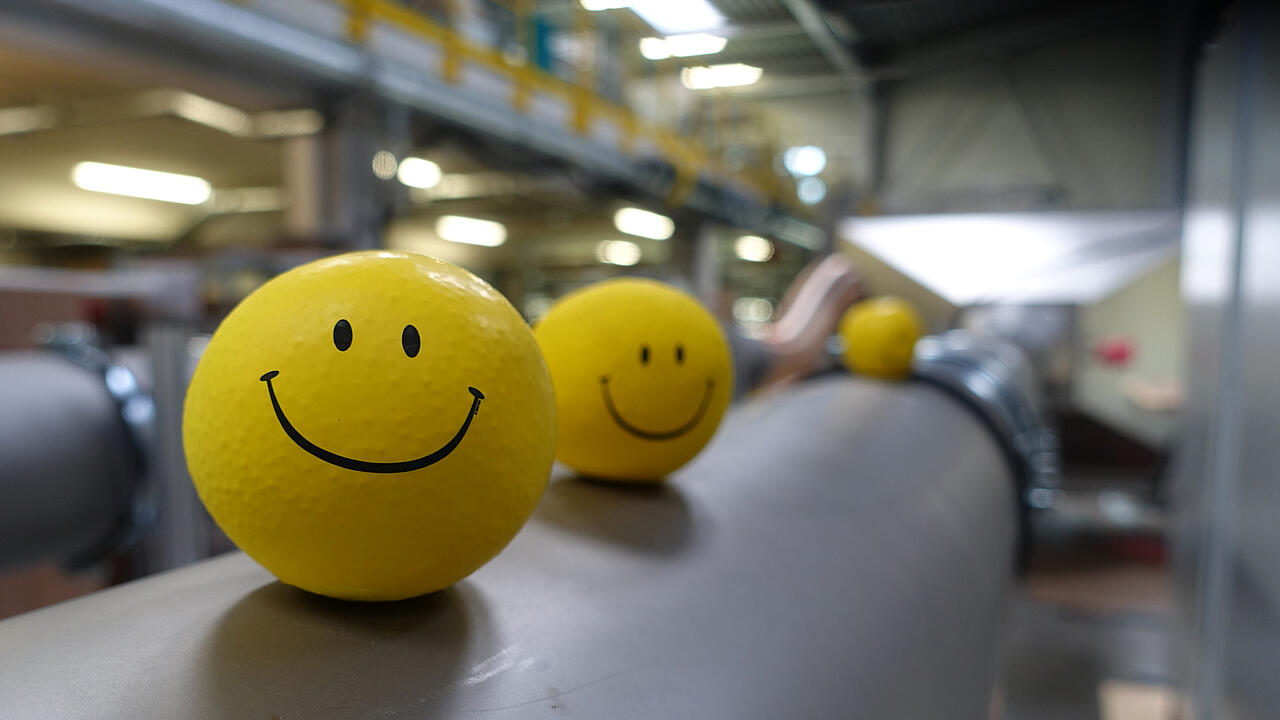 Produktionshalle mit gelben Smileybällen auf Prüfkanal