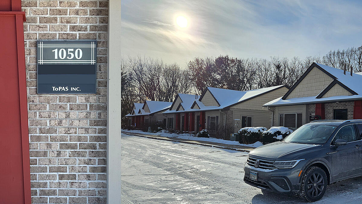 Sign of Topas Inc entrance, next to it a winterly street with cars